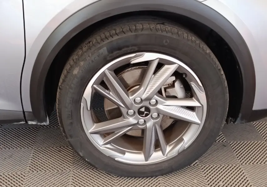 Gros plan sur la roue avant gauche d’un DS7 Crossback gris clair, mettant en valeur la jante alliage au design moderne.