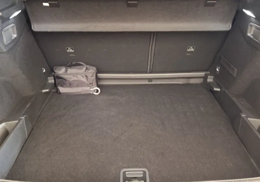 Vue intérieure du coffre spacieux du DS7 Crossback E-TENSE 225 Business, avec tapis noir et sac de rangement.