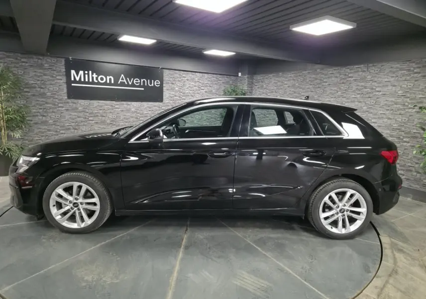 Audi A3 Sportback noire vue de profil côté gauche, avec jantes alliage 5 branches et calandre noire mate.