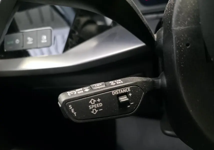 Gros plan sur la commande de régulateur de vitesse adaptatif à gauche du volant d’un Audi A3 Sportback noir 2023.