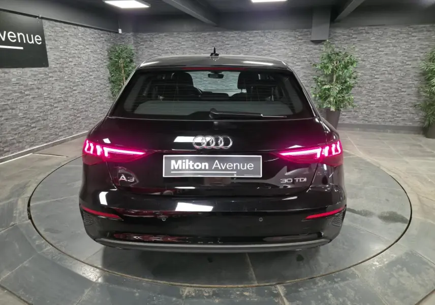 Vue arrière d'une Audi A3 Sportback noire 2023 avec feux LED allumés dans un showroom.