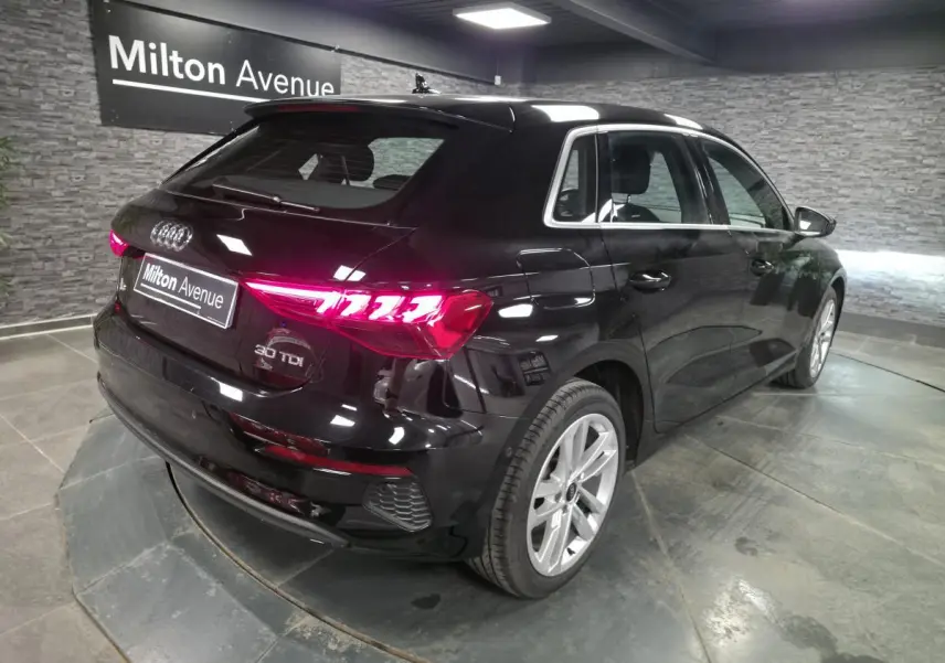 Audi A3 Sportback noir vue 3/4 arrière droit, feux LED allumés et jantes alliage 17 pouces visibles.