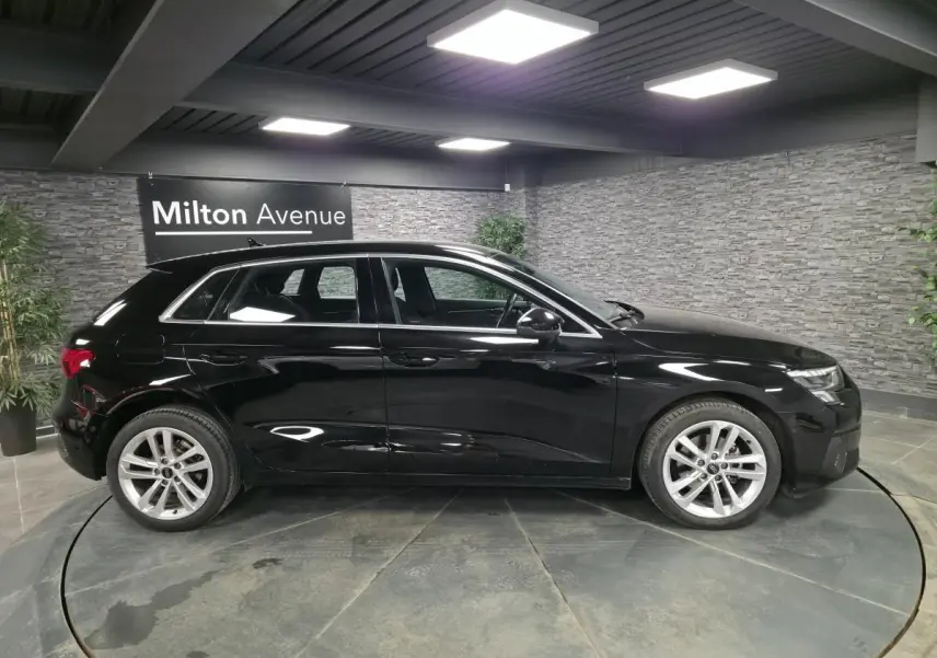Audi A3 Sportback noir vue de profil côté gauche dans un showroom avec jantes alliage 5 branches.