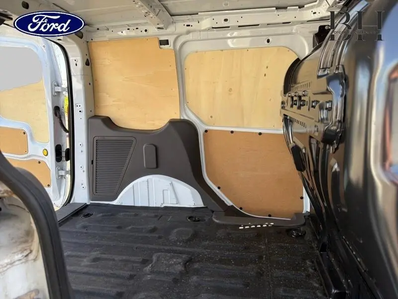 Vue intérieure arrière droite du Ford Transit Connect L1 blanc glacier, montrant la cloison tôlée et le plancher caoutchouc.