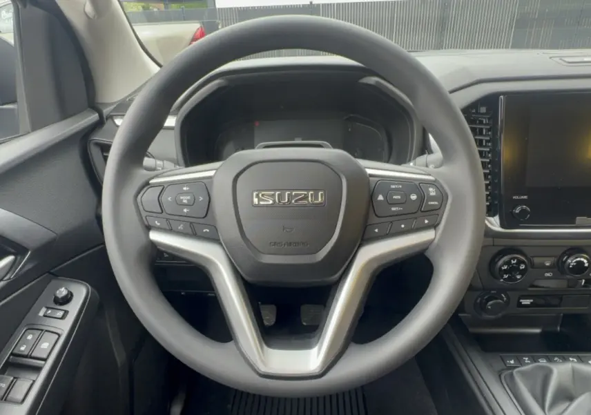 Vue rapprochée du volant multifonctions et tableau de bord noir de l'Isuzu D-MAX 2026 avec écran tactile et commandes au volant.