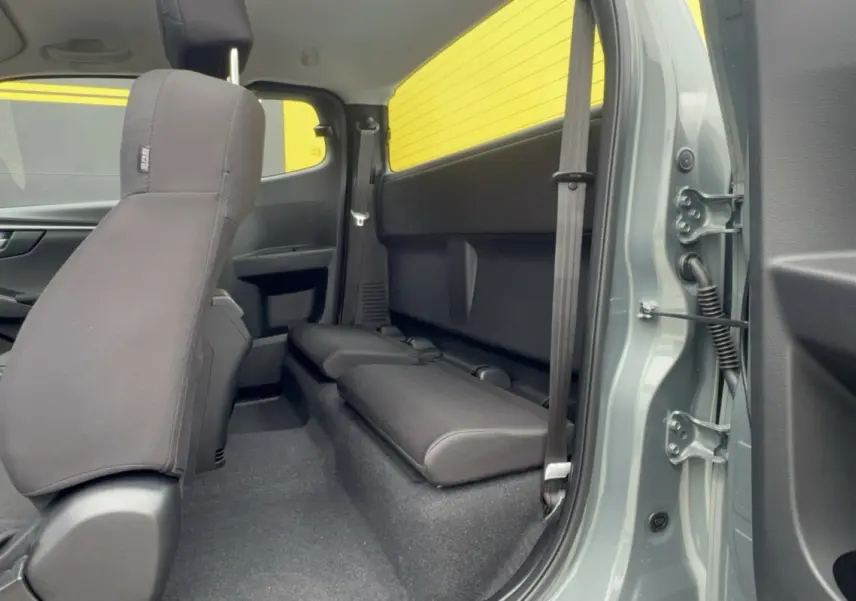 Vue intérieure arrière droite du pick-up Isuzu D-MAX 2.2 TD 164 Space Evolution, sièges strapontins noirs, carrosserie vert Inishmore.