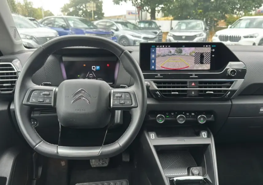 Intérieur de la Citroën C4 1.5 BlueHDi 130 gris, vue frontale sur le volant cuir et l'écran tactile affichant la caméra de recul.