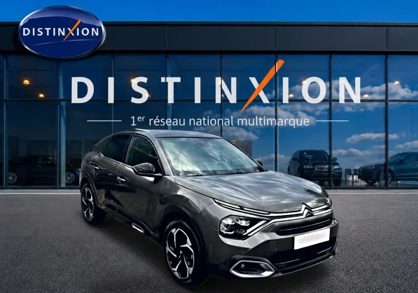 Citroën C4 gris vue 3/4 avant droit, avec jantes alu et phares LED, devant une vitrine Distinxion.