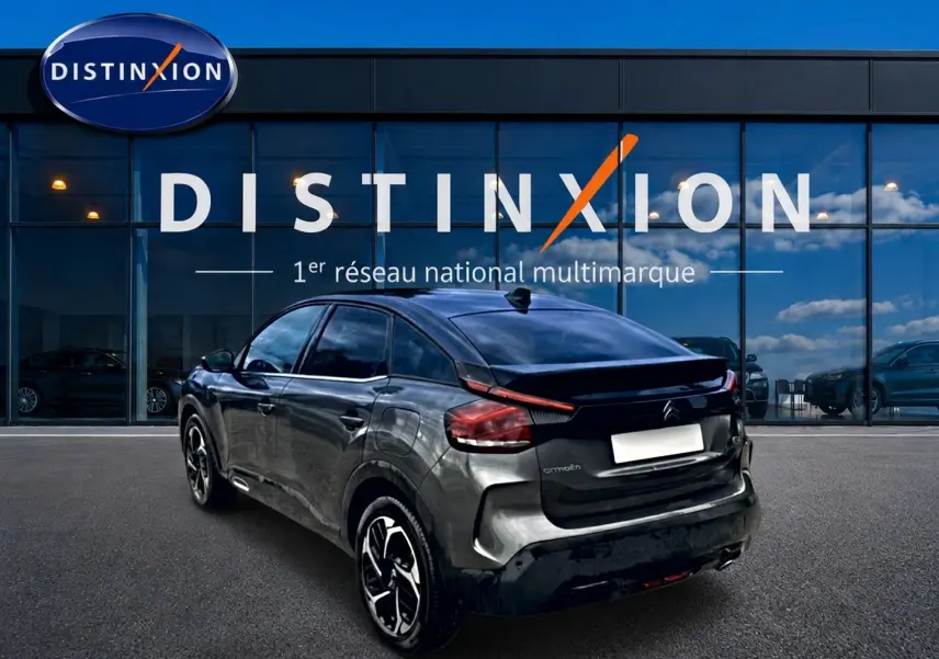 Vue 3/4 arrière droite d'une Citroën C4 gris métallisé 2024, avec jantes alu et feux arrière LED distinctifs.