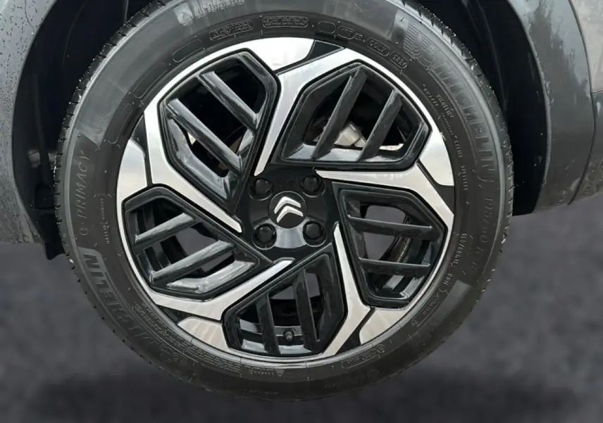 Gros plan sur la jante alu noire et argentée d'une Citroën C4 gris, avec logo Citroën au centre.