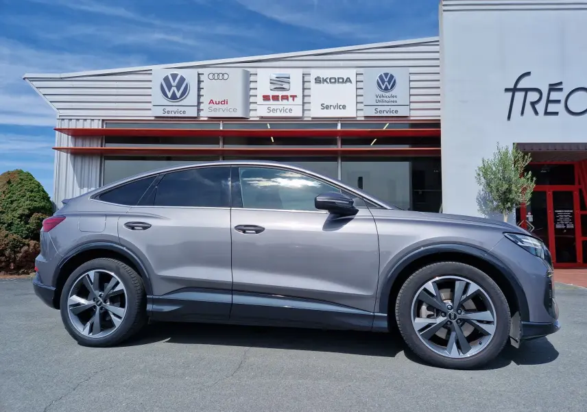 Profil côté gauche de l'Audi Q4 E-TRON Sportback gris thyphon 2022, avec jantes alliage et lignes fluides électriques.