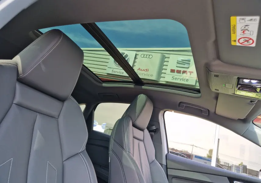 Vue intérieure de l'Audi Q4 E-TRON SPORTBACK 50 quattro gris thyphon, mettant en valeur les sièges en cuir noir et le toit panoramique.