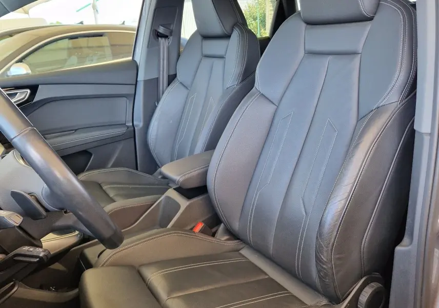 Vue intérieure côté conducteur de l'Audi Q4 E-TRON Sportback 50 quattro 2022 avec sièges cuir noir et toit panoramique.