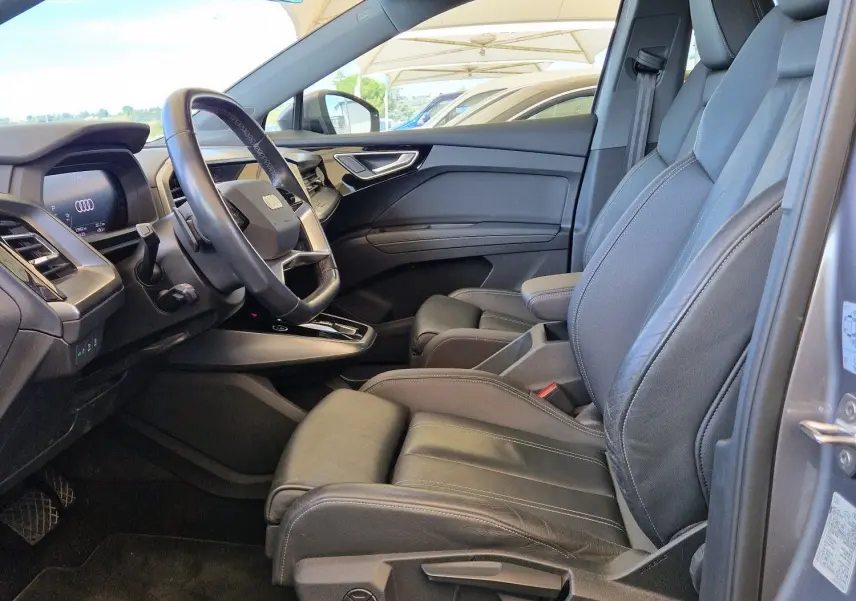 Vue intérieure côté conducteur de l'Audi Q4 E-TRON Sportback gris thyphon, sièges cuir noir et toit panoramique.