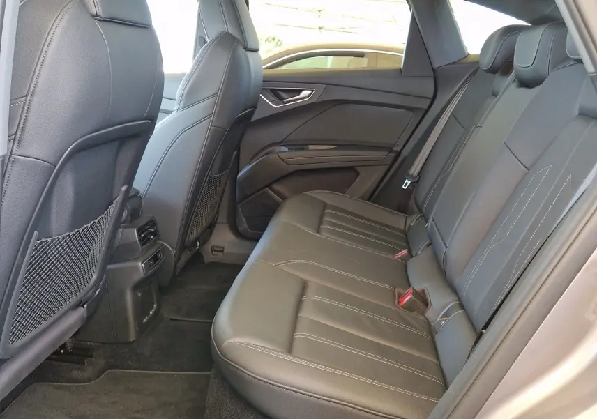 Vue intérieure arrière côté gauche de l'Audi Q4 E-TRON Sportback 50 quattro 2022 avec sièges cuir noir et toit panoramique.