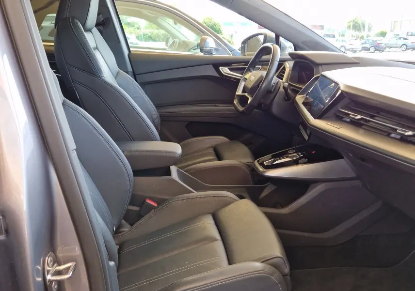 Intérieur côté conducteur de l'Audi Q4 E-TRON SPORTBACK gris thyphon 2022, sièges cuir noir et toit ouvrant panoramique.