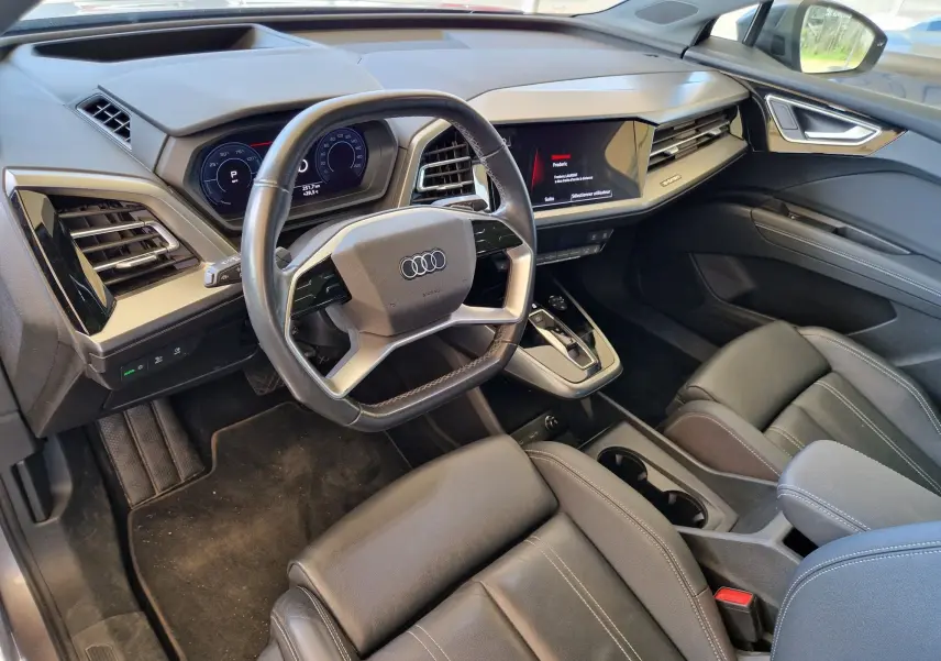 Intérieur noir de l'Audi Q4 E-TRON Sportback 50 quattro 2022, vue côté conducteur sur tableau de bord et volant multifonction.