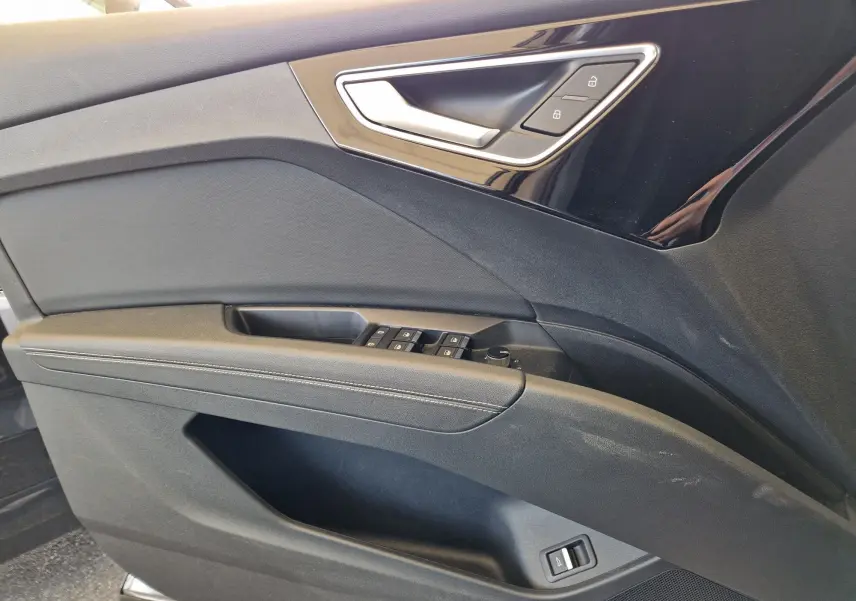 Détail de la porte côté gauche de l'Audi Q4 E-TRON Sportback gris thyphon avec commandes de vitres et verrouillage.