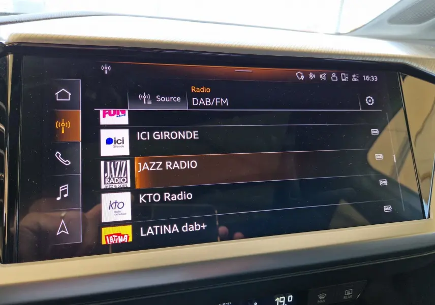 Écran tactile central de l'Audi Q4 E-TRON SPORTBACK 50 quattro gris thyphon affichant les stations radio DAB/FM.