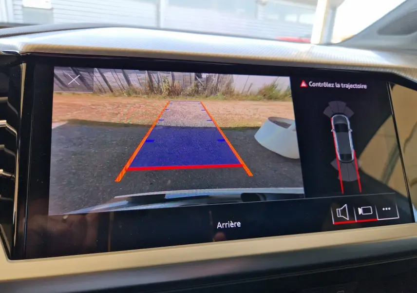 Vue de l'écran de recul de l'Audi Q4 E-TRON Sportback gris thyphon, affichant les lignes de guidage et l'alerte de trajectoire.