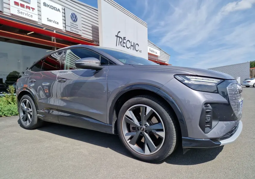 Audi Q4 E-TRON Sportback gris thyphon en vue 3/4 avant droit, soulignant ses jantes modernes et son design électrique élégant.