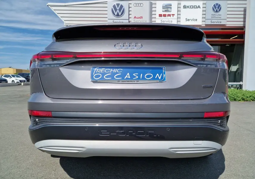 Vue arrière d'un Audi Q4 E-TRON Sportback gris thyphon avec bande lumineuse et logo quattro visible.