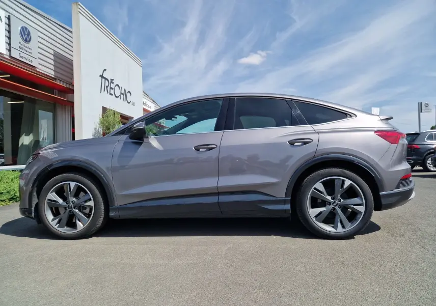 Audi Q4 E-TRON Sportback gris thyphon vu de profil côté gauche, soulignant ses jantes modernes et sa silhouette élancée.
