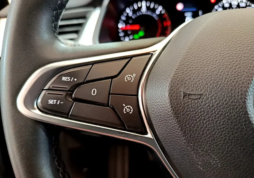 Gros plan sur les commandes du régulateur de vitesse à gauche du volant noir du Renault Captur Business 2020.