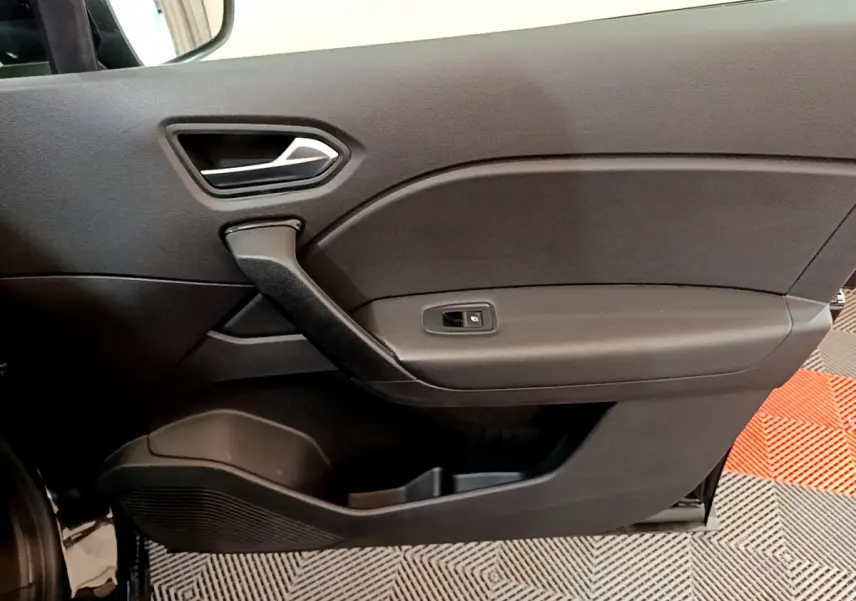 Vue rapprochée de la porte intérieure côté gauche noire du Renault Captur Business Blue dCi 95, avec poignée et commande de vitre.