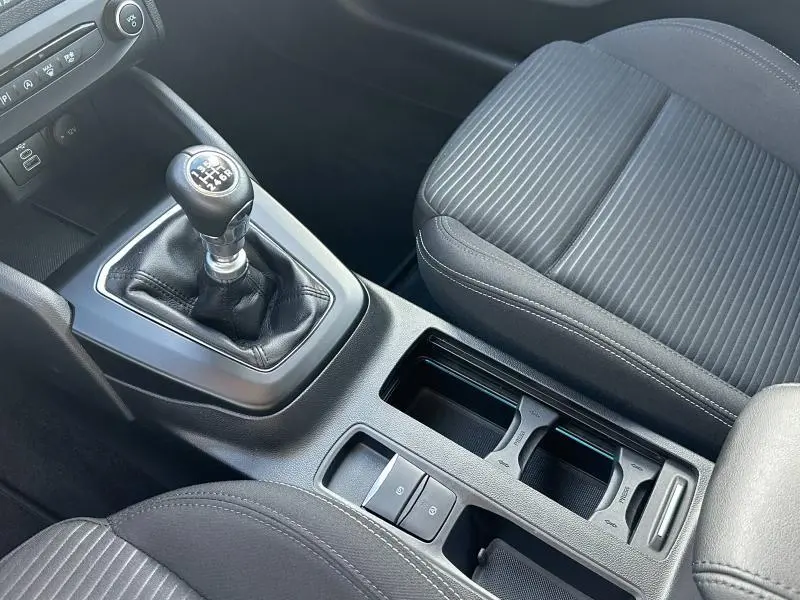 Vue rapprochée de la console centrale noire avec levier de vitesse manuel et sièges en tissu rayé dans une Ford Focus 2023.