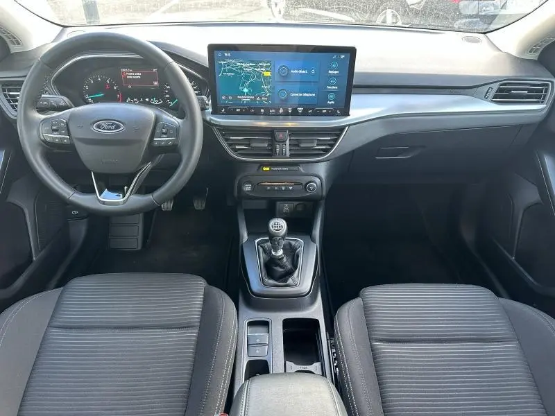 Intérieur de Ford Focus 1.0 Ecoboost 2023 vu de face, tableau de bord noir avec écran tactile et levier de vitesses manuel.