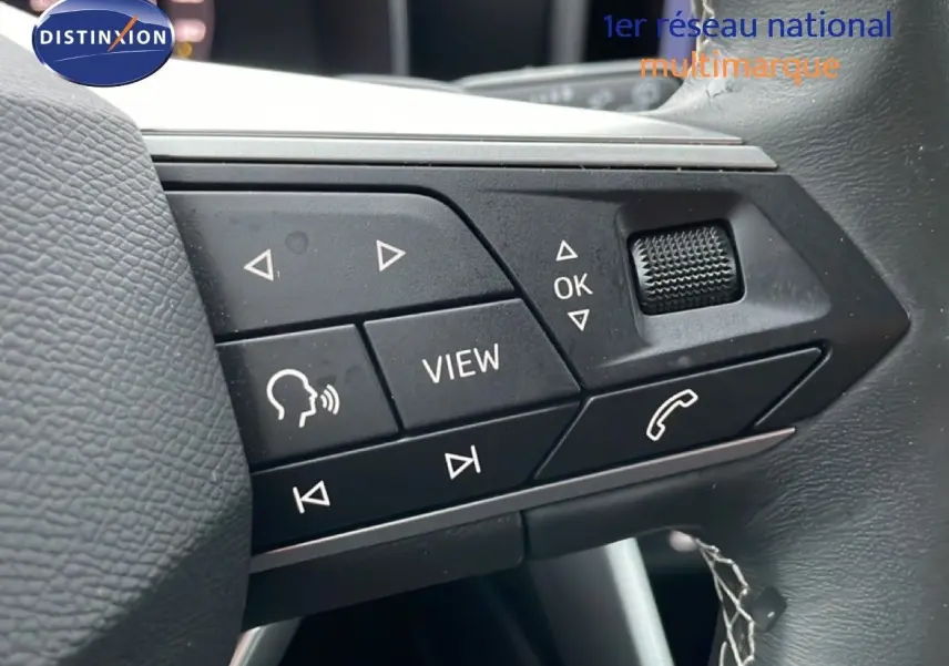 Gros plan sur les commandes multifonctions du volant en cuir noir d’une SEAT LEON ST Bleu Fjord 2025.