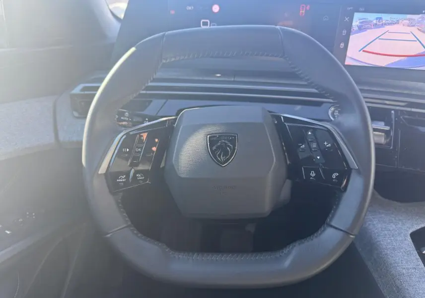 Vue frontale du volant cuir noir du Peugeot 3008 Hybrid 145 e-DCS6 Allure 2025 avec commandes intégrées et tableau de bord numérique.