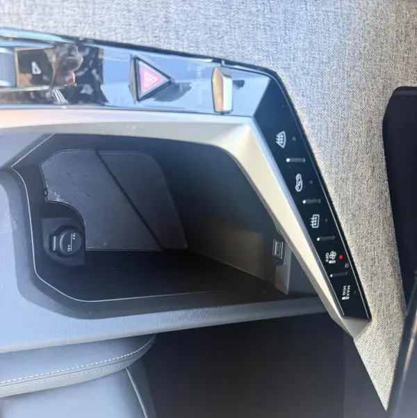 Vue rapprochée de la console centrale grise du Peugeot 3008 Hybrid 145 e-DCS6 Allure avec commandes tactiles et prise 12V.
