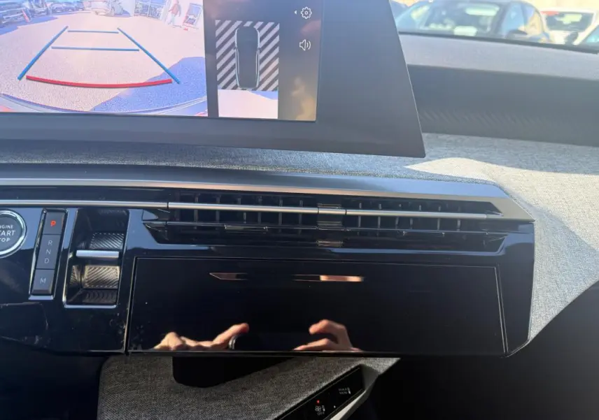 Vue intérieure du tableau de bord du Peugeot 3008 Hybrid gris, avec écran de caméra de recul et commandes modernes.