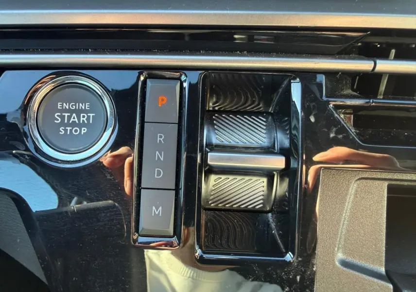 Gros plan sur la console centrale noire brillante du Peugeot 3008 Hybrid avec bouton start/stop et commande de boîte automatique.