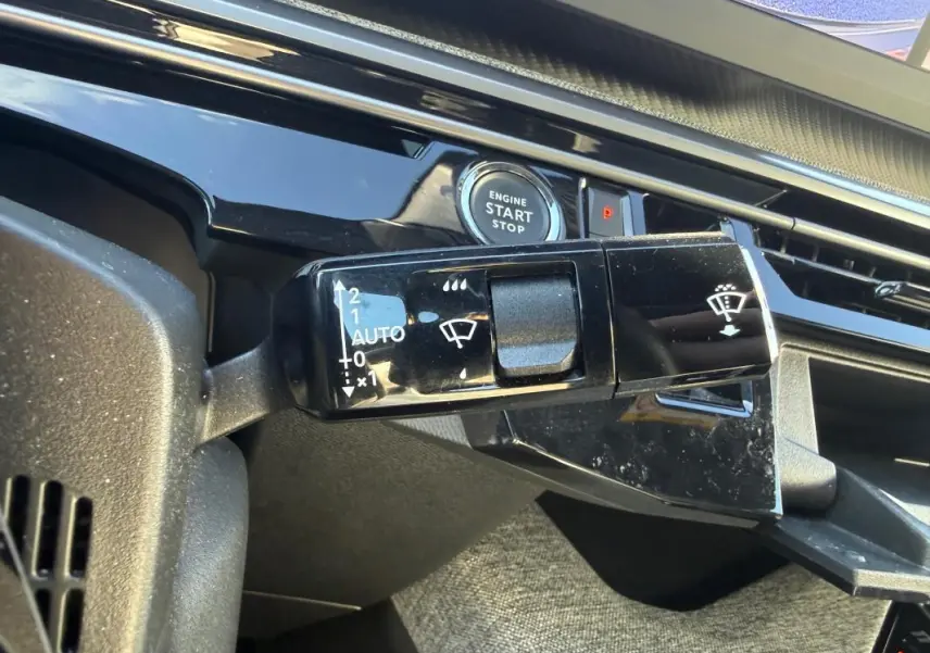 Gros plan sur la commande d’essuie-glace et bouton start/stop du tableau de bord gris du Peugeot 3008 Hybrid 145 Allure 2025.