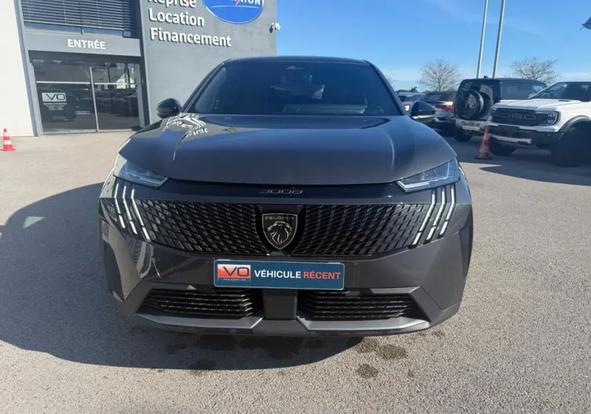Vue frontale d'un Peugeot 3008 Hybrid gris avec calandre noire et feux LED distinctifs, stationné en extérieur.