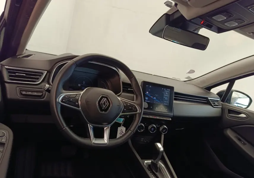 Vue intérieure côté conducteur de la Renault Clio Business E-TECH 140 avec volant cuir et écran tactile central allumé.