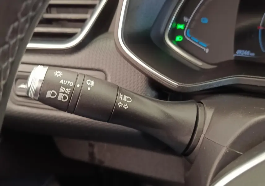 Gros plan sur la manette de commande des phares et clignotants dans l’habitacle d’une Renault Clio Business E-TECH blanche.