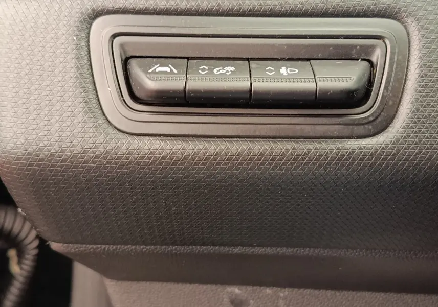 Gros plan sur les boutons de commande d'aide à la conduite dans l'habitacle noir d'une Renault Clio Business E-TECH 140.