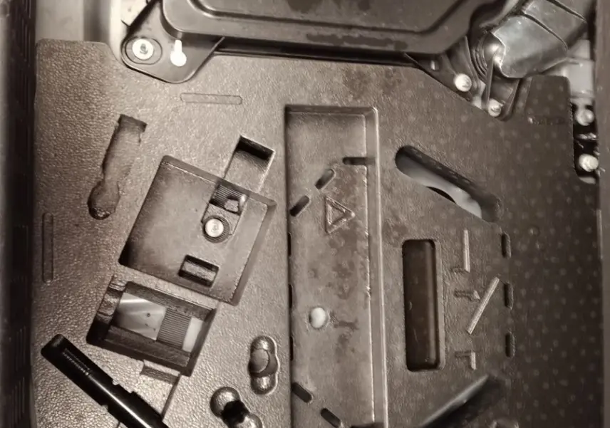 Vue rapprochée du compartiment de rangement sous le plancher de coffre de la Renault Clio Business E-TECH 140 blanche.