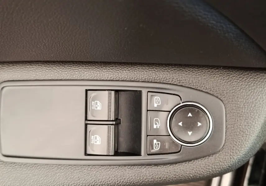 Gros plan sur les commandes de lève-vitres et réglage des rétroviseurs côté conducteur d'une Renault Clio Business E-TECH blanche.