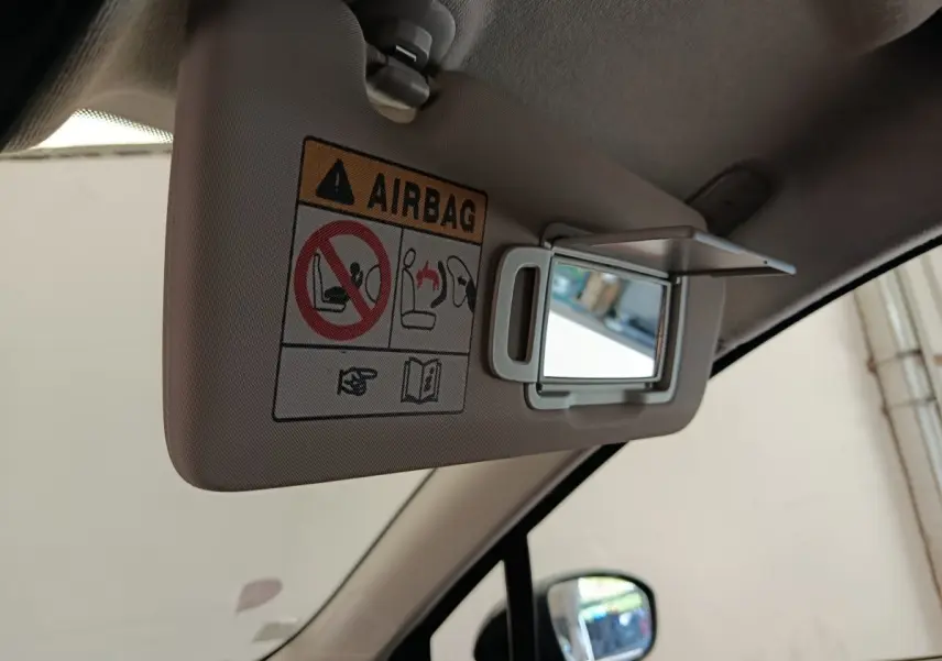 Miroir de courtoisie ouvert sur pare-soleil beige côté conducteur dans l'habitacle d'une Renault Clio blanche.