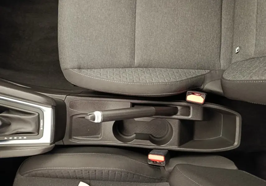 Vue plongeante sur la console centrale noire de la Renault Clio Business E-TECH 140 avec frein à main manuel et sièges tissu gris.