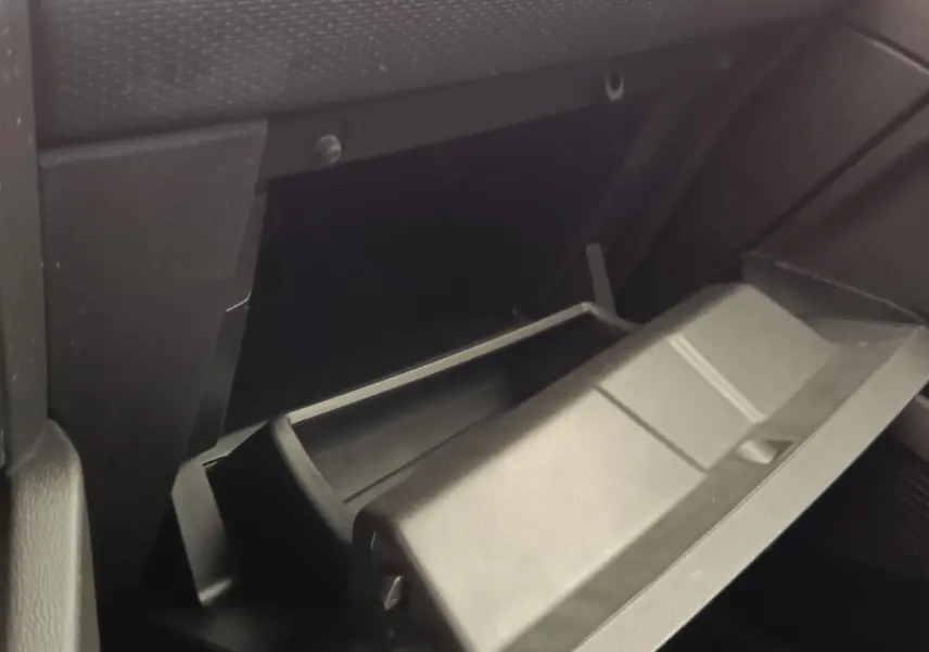 Gant de boîte à gants ouvert côté passager dans l'habitacle sombre d'une Renault Clio Business E-TECH 140 blanche.