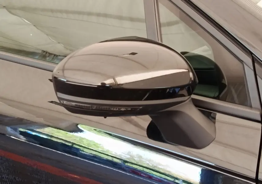 Gros plan sur le rétroviseur droit noir brillant d’une Renault Clio Business E-TECH 140 blanche, reflet visible sur la carrosserie.