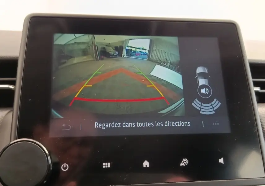 Écran tactile intérieur montrant la caméra de recul et l’aide au stationnement de la Renault Clio Business E-TECH blanche.