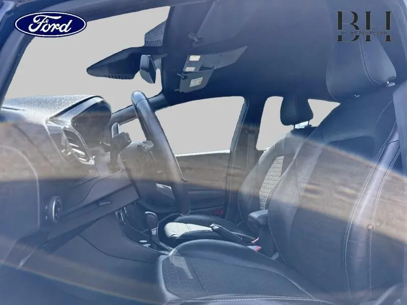 Vue intérieure côté conducteur de la Ford Fiesta 2018 avec sièges sport cuir-tissu gris et volant cuir noir.