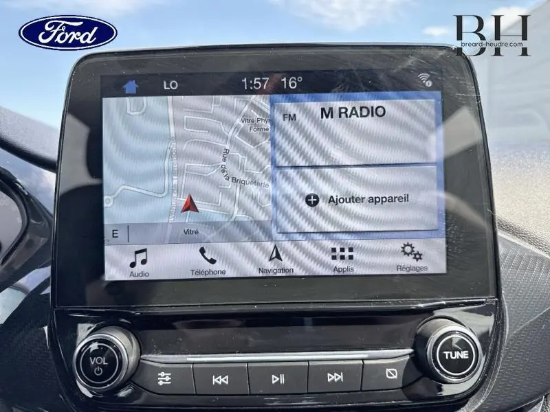 Écran tactile central de la Ford Fiesta 2018 affichant la navigation et la radio, avec commandes audio en bas.